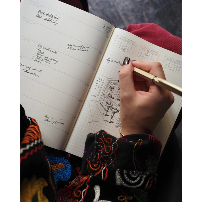 Person writing in a planner with a colorful sleeve